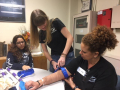 Chelsea applies a tourniquet as Gianna observes.